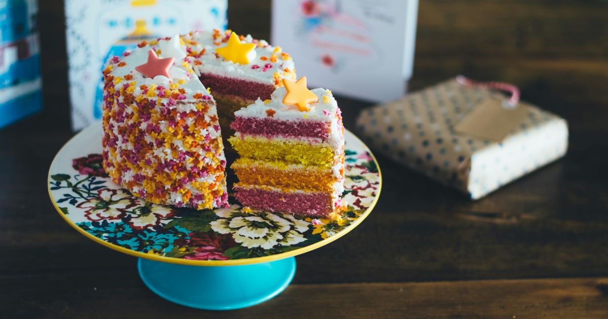 A vibrant cake with a slice taken out, beautifully presented on a plate, showcasing its colorful layers.